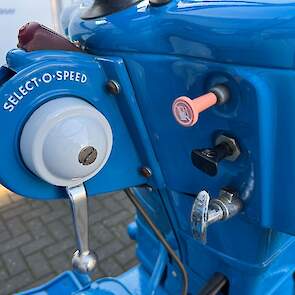 De versnellingen van de Select-O-Speed worden ingelegd met een hendel, naar voren duwen is opschakelen, naar je toe trekken is terugschakelen. Met de PTO-knop rechtsonder wordt de aftakas in- en uitgeschakeld. Ook daarvoor hoef je niet te ontkoppelen.